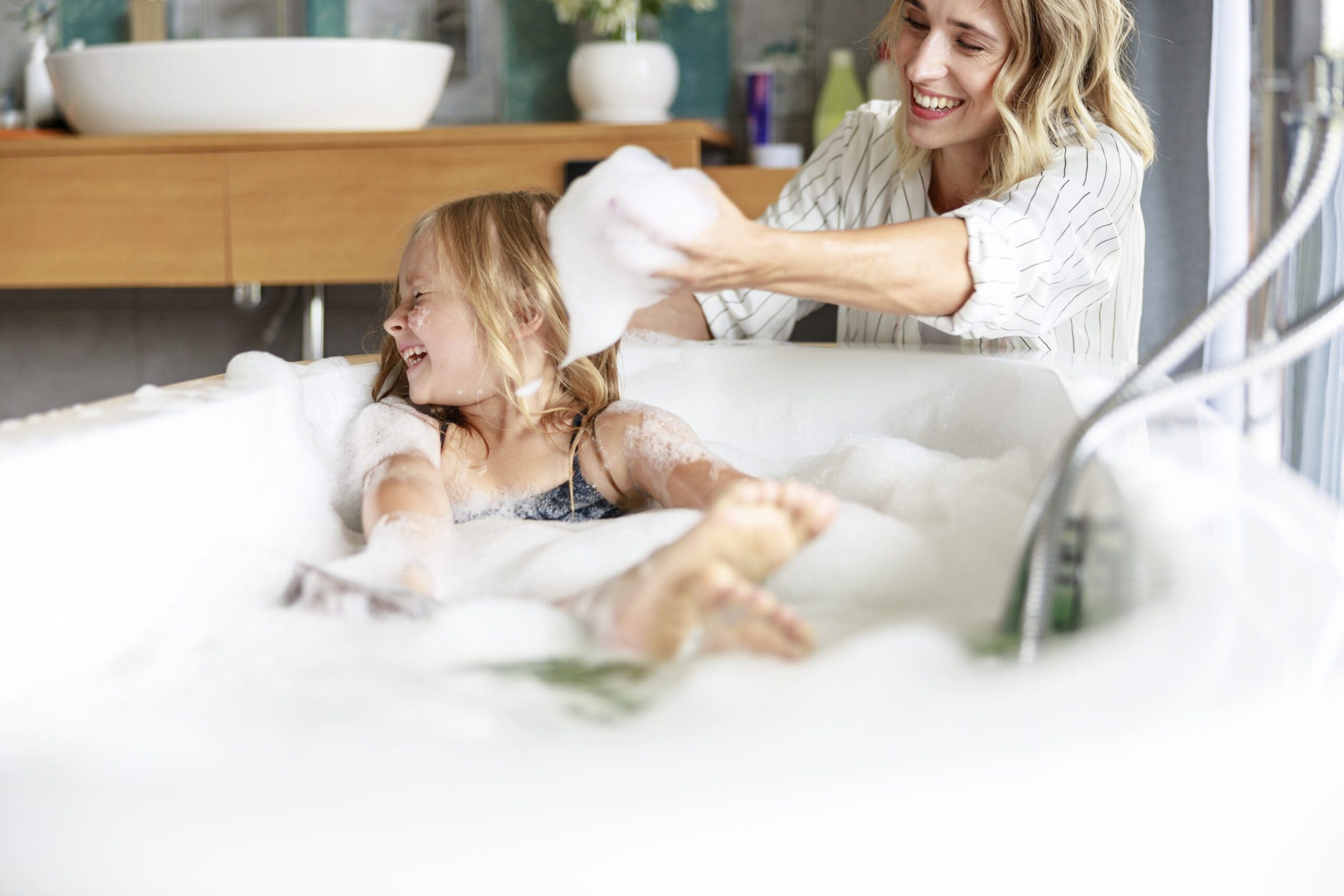 una bambina felice con la madre. Tiene la schiuma sulle mani