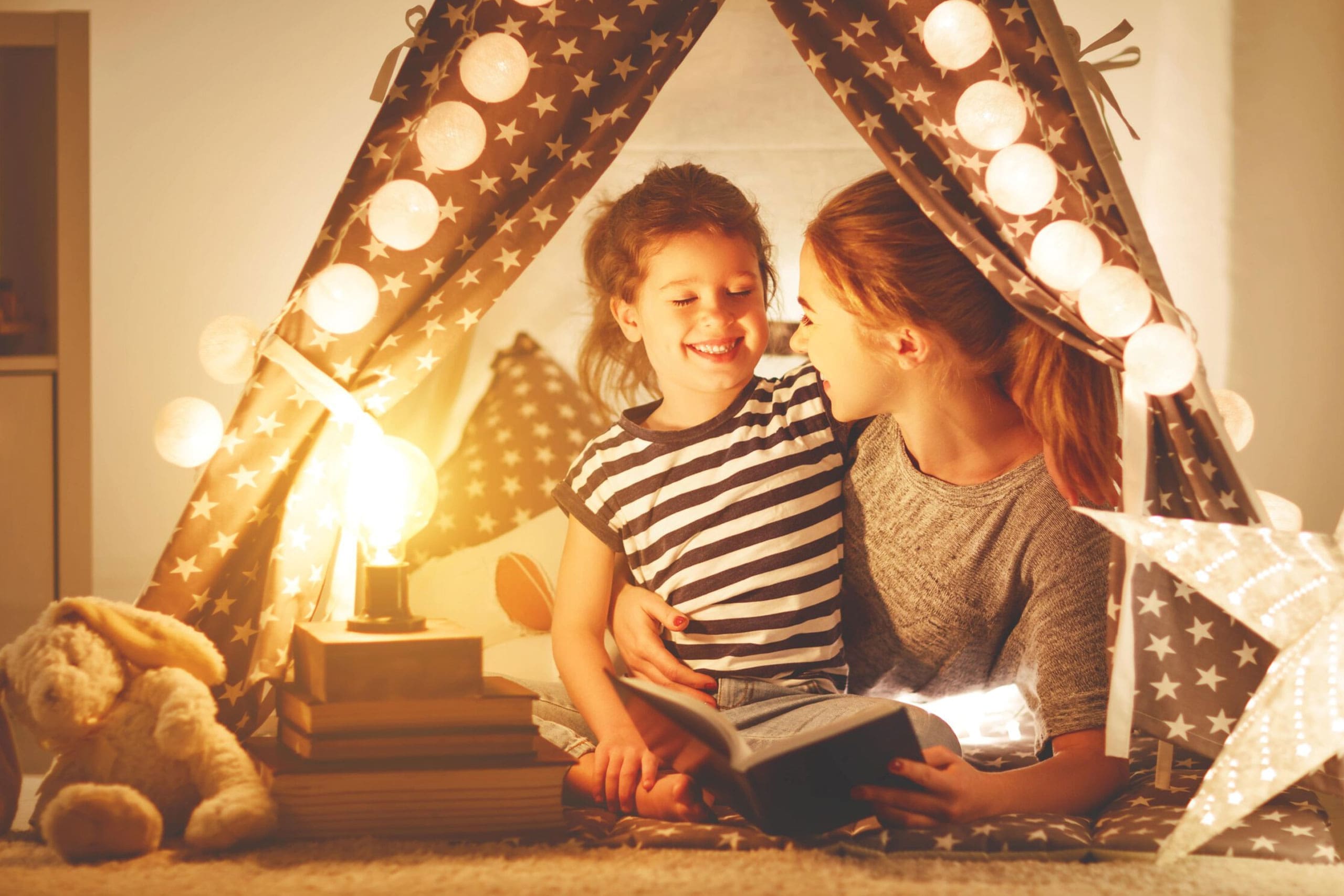 un genitore e il suo bambino felice di leggere un libro. Sullo sfondo ci sono alcune luci decorative